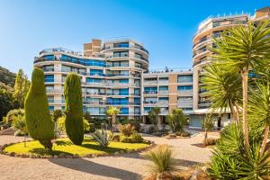 un grand immeuble d'appartements avec des arbres devant lui dans l'établissement Pretty Flat in the Sun, à Mandelieu-la-Napoule