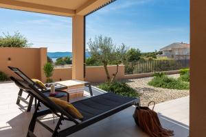 a patio with a chair and a table on a balcony at Luxury Villa Wave heated pool sauna in Sveti Filip i Jakov