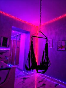 Una habitación con luces violetas y un columpio colgando de una cadena. en Secret love room, en Bucarest
