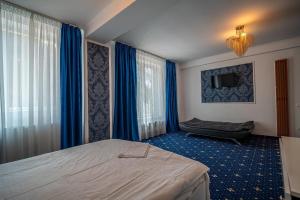 a bedroom with a bed and a tv and blue curtains at Blue Hotel Boutique & Spa in Buşteni