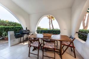 a room with a table and chairs and two windows at Villa Judith in Porto Columbu - Perdʼe Sali