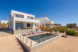 a large white house with a swimming pool and chairs at Villa Aguamarina by Villa Plus in Cala en Forcat