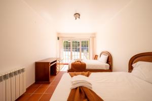 ein Schlafzimmer mit zwei Betten und einem Schreibtisch und einem Fenster in der Unterkunft Burgo D Sancho I 17 in Amoreira + 69 Fotos