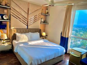 a bedroom with a large bed with a large window at Elysium Designer Executive Apartments Facing Centaurus Mall Islamabad in Islamabad +102 photos