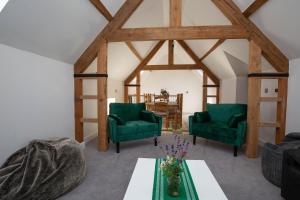 a living room with two green chairs and a table at The Stables in Mollington