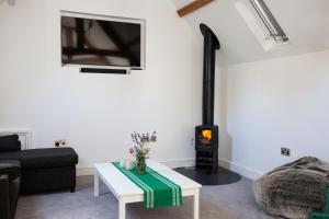 a living room with a couch and a stove at The Stables in Mollington