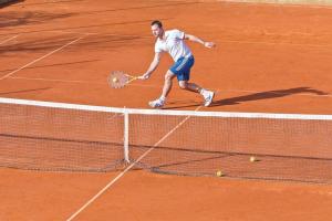 a man holding a tennis racket on a tennis court at Eg Marjetka Bis 9 in Rab