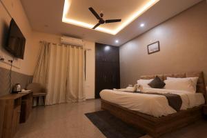 a bedroom with a large bed with a ceiling fan at Hotel Mango Tree, Vrindavan in Vrindāvan
