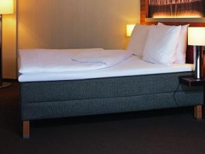 a bed in a hotel room with white sheets and pillows at Mövenpick Hotel Zürich-Regensdorf in Regensdorf