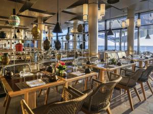 a restaurant with tables and chairs and a view of the ocean at Mövenpick Hotel Gammarth Tunis in Gammarth