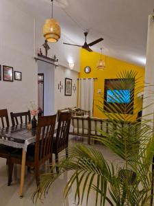 a dining room with a table and chairs and a yellow wall at Cozy Cabana - Maynard Palace in Benaulim