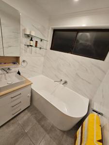 a white bathroom with a tub and a sink at Home Near Melbourne Airport in Meadow Heights