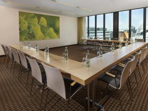 una grande sala conferenze con un lungo tavolo e sedie di Mövenpick Hotel Frankfurt City Messe a Francoforte sul Meno
