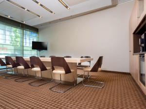 una sala conferenze con tavolo e sedie di Mövenpick Hotel Frankfurt City Messe a Francoforte sul Meno