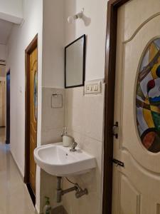a bathroom with a sink next to a door at Cozy Cabana - Maynard Palace in Benaulim