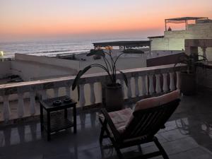 a chair and a table on a balcony with the ocean at Tayyurt Blue waves Beach house's in Oulad Akkou
