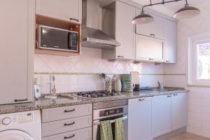 cocina blanca con fogones y microondas en Pomegranate Haus, en Melides 15 fotos más