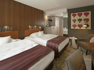a hotel room with two beds and a living room at Mövenpick Hotel Münster am Aasee in Münster