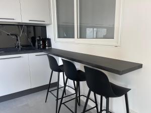a kitchen with a black counter and stools at Brand New Seafront Apartment in Sliema