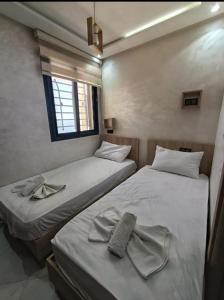 two twin beds in a room with a window at les appartements vip madinat bades alhoceima in Al Hoceïma