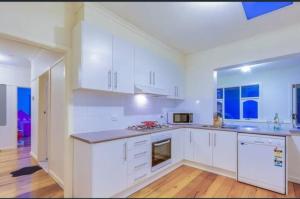 a kitchen with white cabinets and a stove top oven at Comfy & Budget-Friendly Home in Balwyn - Quiet & Close to Melbourne CBD in Balwyn