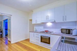 a kitchen with white cabinets and a sink at Comfy & Budget-Friendly Home in Balwyn - Quiet & Close to Melbourne CBD in Balwyn