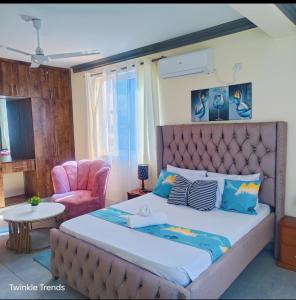 a bedroom with a large bed and a chair at LES INTERNATIONAL in Mombasa +25 photos