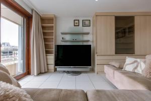 un salon avec un canapé et une télévision à écran plat dans l'établissement Appa - Beachfront & Harbour Stay with Balcony, à Ostende