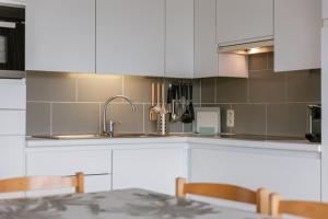 une cuisine avec des armoires blanches et un évier dans l'établissement Appa - Beachfront & Harbour Stay with Balcony, à Ostende 26 autres photos