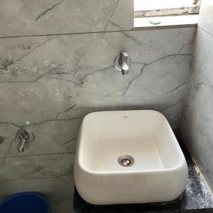 a white sink in a bathroom with a marble wall at Hotel Radhe Kudasan in Jāmb