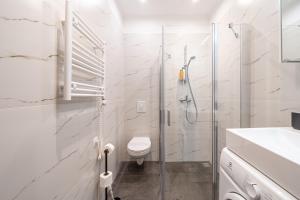 a white bathroom with a shower and a toilet at Forest view front line apartment on Dzintaru avenue in Jūrmala +31 photos