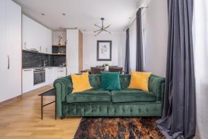 a living room with a green couch with yellow pillows at Forest view front line apartment on Dzintaru avenue in Jūrmala