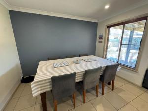 mesa de comedor con sillas y mantel a rayas en Comfy and relaxing stay - Rest Easy Mudgee Cottage, en Mudgee