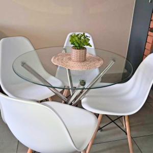 una mesa de cristal con sillas blancas y una planta en ella en Waterfall Ridge Professional Apartment, en Midrand