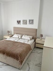a white bedroom with a bed and two night stands at Apartment Elis in Kamëz