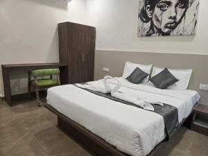 a bedroom with a large bed with a painting on the wall at Hotel EVA in Gundipet