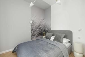 a bedroom with a bed with a gray blanket at Premium & Elegance Apartments with Pool by Noclegi Renters in Sianozety