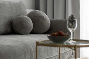 a couch with pillows and a bowl of food and a wine glass at Premium & Elegance Apartments with Pool by Noclegi Renters in Sianozety +85 photos