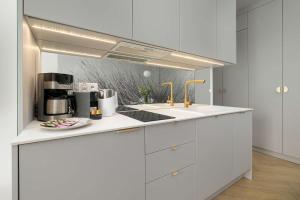 a white kitchen with a sink and a stove at Premium & Elegance Apartments with Pool by Noclegi Renters in Sianozety