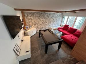 a living room with a red couch and a pool table at Spacious 2 bedroom apartment in Engelberg