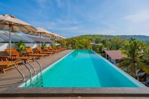 a swimming pool with chairs and umbrellas on a resort at The Passport Hotel in Assagao