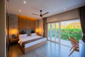a bedroom with a large bed and a balcony at The Passport Hotel in Assagao
