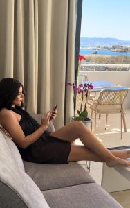 Una donna seduta su un divano che guarda il suo cellulare di Aptos Laguna Premium a Puerto de Mazarrón Altre 71 foto