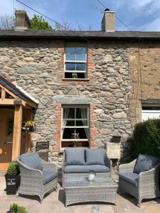 a stone house with two chairs and a table at River Cottage in Conwy