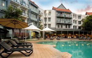 a pool with chairs and umbrellas next to a building at Pagoda Resort & Spa in Perth