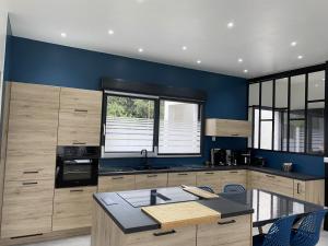 a kitchen with wooden cabinets and a blue wall at Gite de l'etoile in Rocroi