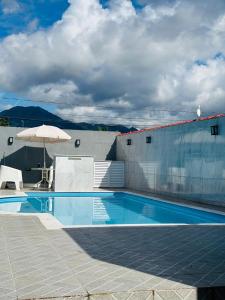 - une piscine avec un parasol à côté d'un bâtiment dans l'établissement CASA COM PISCINA - PeRUIBE, à Peruíbe