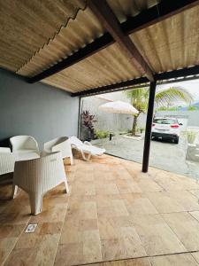 une terrasse avec des chaises blanches et un parasol dans l'établissement CASA COM PISCINA - PeRUIBE, à Peruíbe