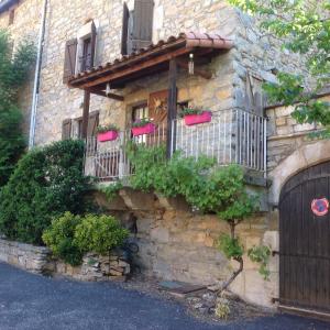 a stone building with a balcony with flowers on it at CARDABELLE maison authentique à louer in Millau