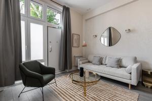 a living room with a couch and a chair and a mirror at Waou Glam Plaza España in Madrid